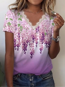 Dettaglio dell'elegante scollo a V con pizzo bianco e stampa floreale viola