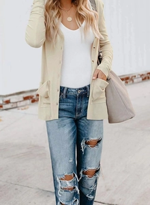 Detail of beige knit cardigan featuring large symmetrical pockets and ribbed cuffs