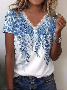 Dettaglio dello scollo a V con pizzo a ciglia e stampa a foglie blu sulla maglietta