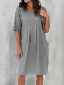 Detail view of the pleated chest design and side pockets on a grey cotton linen dress