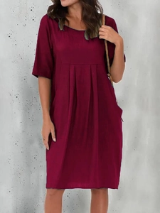 Detail of burgundy linen dress featuring pleated crew neck and casual loose fit cut