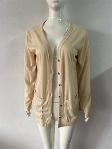 Detail view of the ribbed texture and dark buttons on a beige V-neck knit cardigan