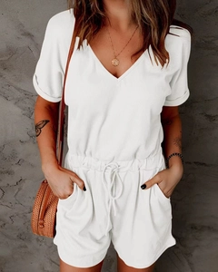 Detail of white ribbed knit romper with V-neckline, drawstring waist, and side pockets