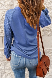Detail of waffle knit fabric and lace patchwork sleeves on a blue long sleeve top