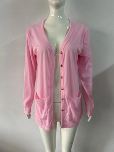 Detailed view of pink knitted cardigan with ribbed texture, V-neck, and brown buttons