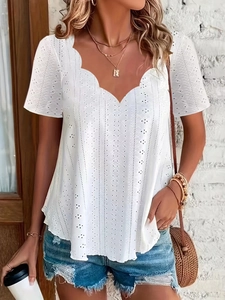 Detail der weißen Bluse mit gewelltem V-Ausschnitt und filigraner Lochstickerei