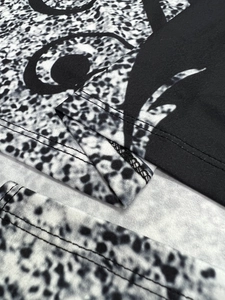 Detail of double-needle stitching on black and white animal print geometric t-shirt