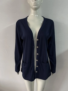Detail of dark blue V-neck ribbed knit cardigan featuring white buttons and front pockets