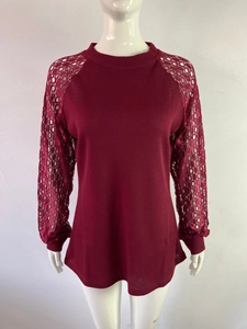 Detailed view of wine red waffle knit texture and hollow lace sleeves on women's top