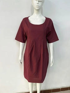 Detail view of burgundy pleated dress showing the crew neck and waistline texture