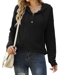 Détail de la maille gaufrée noire sur ce sweat à capuche ample avec boutons et poignets