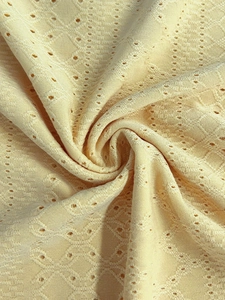 Nahaufnahme des blassgelben Strickstoffs mit floralen Lochmustern und weicher Textur