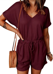 Detail of burgundy V-neck rib-knit romper featuring drawstring waist and rolled sleeves