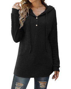 Détail de la texture gaufrée sur un pull noir à capuche avec boutons et cordon de serrage
