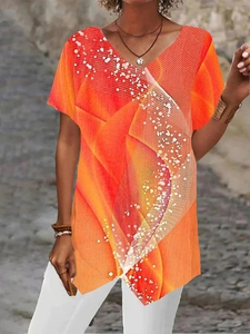 Detail of V-neck short sleeve top featuring orange abstract prints and asymmetric hem