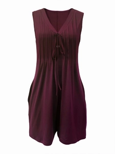 Detail of V-neck sleeveless romper with button accents and pleats in deep purple fabric
