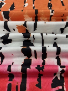 Detail of soft tie-dye fabric with orange to pink gradient and black abstract stripes