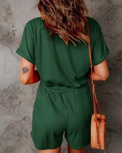Detail of dark green ribbed jumpsuit featuring rolled sleeves and a waist-cinching fit