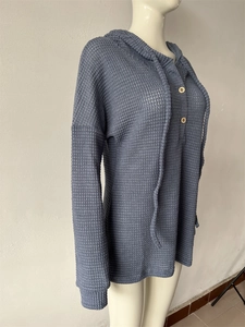 Détails de la maille gaufrée et des boutons sur un pull à capuche bleu marine