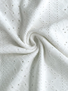 Macro detail of white eyelet broderie anglaise fabric with geometric hollow patterns
