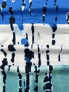Macro detail of V-neck dress fabric showing blue abstract tie-dye print and knit texture