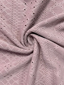 Macro shot of breathable dusty rose pointelle fabric with geometric hollow patterns