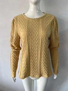Detail of chunky cable knit texture on a yellow crewneck sweater with puff sleeves