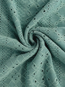 Detail of grey-green hollow embroidery fabric with geometric eyelet texture and jacquard