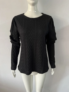 Detail of black knit sweater featuring textured cable patterns and puff sleeve cuffs