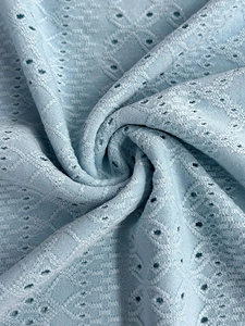 Detaillierte Makroansicht des hellblauen Pointelle-Strickstoffs mit floraler Lochtextur