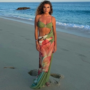 Detailed view of green bikini top with gold accents and floral print beach sarong
