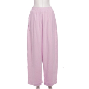 Detailed close-up of light pink high-waisted wide-leg trousers with vertical pleated texture