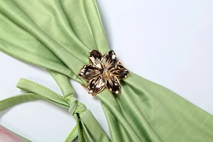 Close-up of the fruit green satin fabric featuring a golden five-petal flower metal buckle