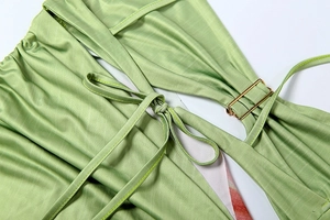 Detail of light green satin dress featuring cutout design with adjustable gold buckle