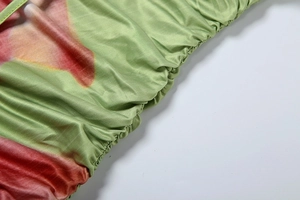 Detail of ruched side seams on a light green floral print bodycon dress for women