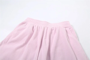 Detail of high waist elastic waistband and side pockets on pink corduroy trousers
