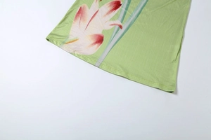 Close-up of lightweight green fabric featuring detailed lily prints and fine vertical textures
