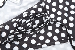 Detail of polka dot jumpsuit showing fabric texture, fine stitching, and waist tie design
