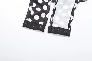 Detailed macro view of black polka dot bodysuit with three metal snap buttons closure
