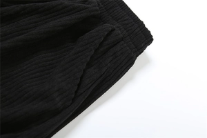 Detail of high waist elastic waistband and side pocket on black ribbed casual trousers