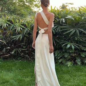 Detail of white satin one-shoulder maxi dress featuring backless design and ribbon tie