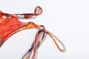 Detailed view of bikini bottom side ties with colorful beads and tie-dye floral pattern