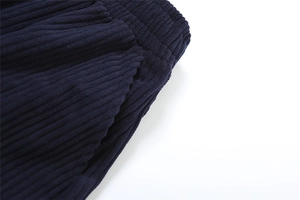 Detail view of navy corduroy trousers showing elastic waist and side pocket texture