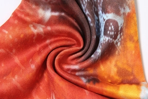 Macro shot showing high-density knitted texture with orange and brown tie-dye pattern