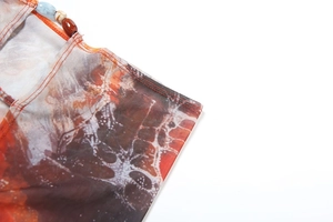 Detailed macro view of orange tie-dye mesh fabric featuring elegant round bead accents