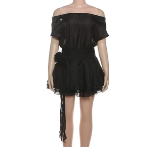 Détail d'une robe courte noire à épaules dénudées avec volants et fleur 3D à la taille