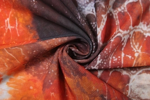 Close-up of lightweight printed orange and brown mesh fabric with pleated texture