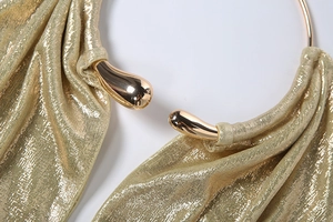 Dettaglio del top a fascia dorato con anello metallico a goccia e tessuto luccicante