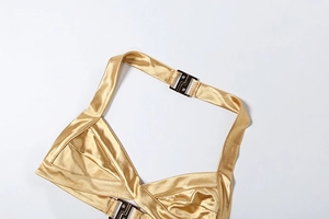 Détail macro du haut licou en satin doré avec tissu plissé et boucles métalliques