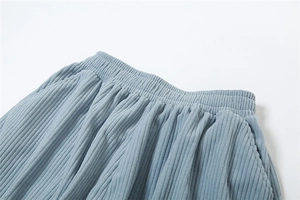 Detail of high waist corduroy trousers in light blue with elastic waistband and pockets